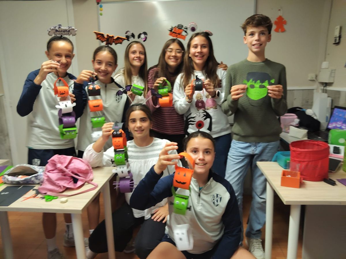 Alumnos adolescentes mostrando sus cadenas de papel de Halloween hechas en inglés