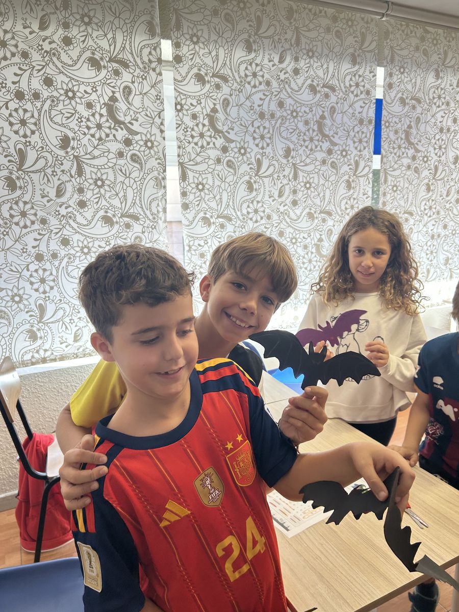 Niños mostrando los murciélagos de papel que han creado en su clase de inglés